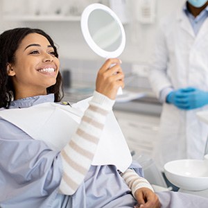 Woman looking at her smile in a handheld mirror