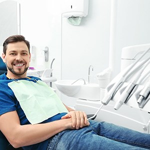 Man leaning back in chair and smiling at oral surgeon’s office