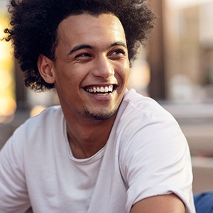 Man in white shirt sitting and smiling