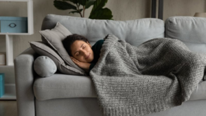 Woman resting on her couch with a cozy blanket